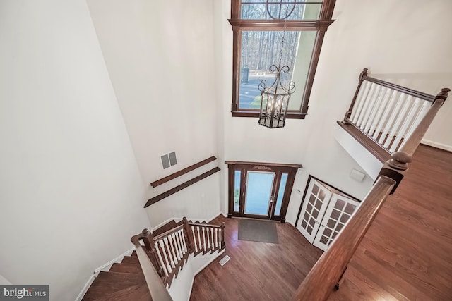 entryway with dark hardwood / wood-style floors, an inviting chandelier, and a high ceiling