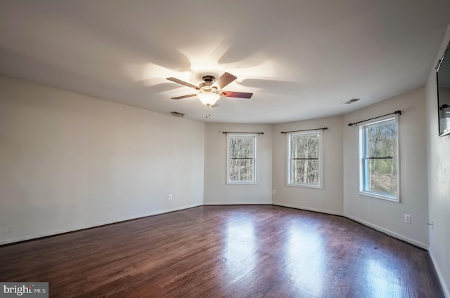 unfurnished room with ceiling fan, a wealth of natural light, and dark hardwood / wood-style flooring