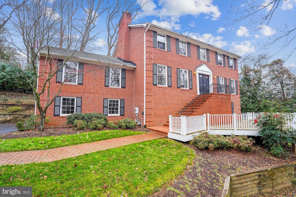 colonial-style house with a front yard and a wooden deck