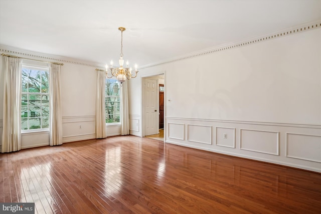 unfurnished room with a chandelier, hardwood / wood-style flooring, and crown molding