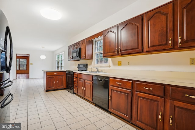 kitchen featuring sink, light tile patterned floors, kitchen peninsula, hanging light fixtures, and black appliances