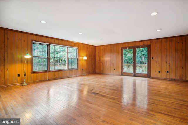 spare room with light hardwood / wood-style floors, crown molding, and wooden walls