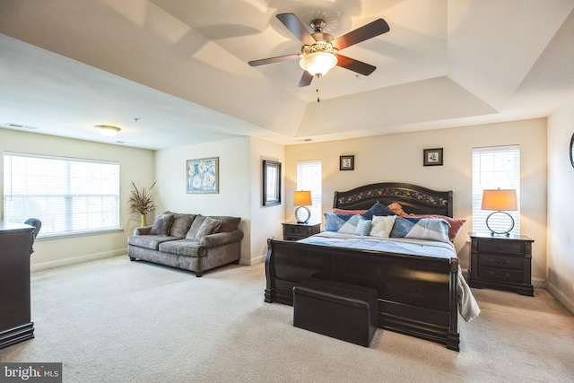 carpeted bedroom with ceiling fan and a tray ceiling