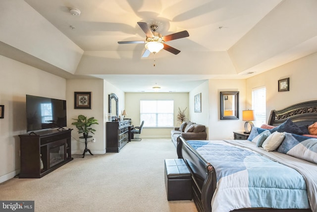 carpeted bedroom featuring a raised ceiling and ceiling fan