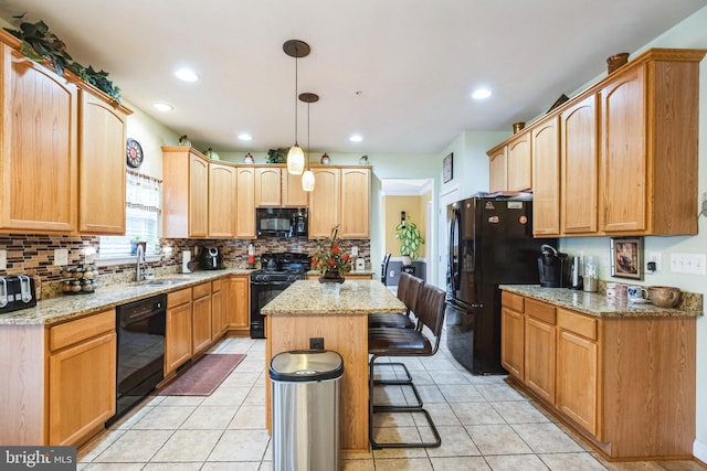 kitchen with black appliances, sink, light stone counters, and a kitchen island