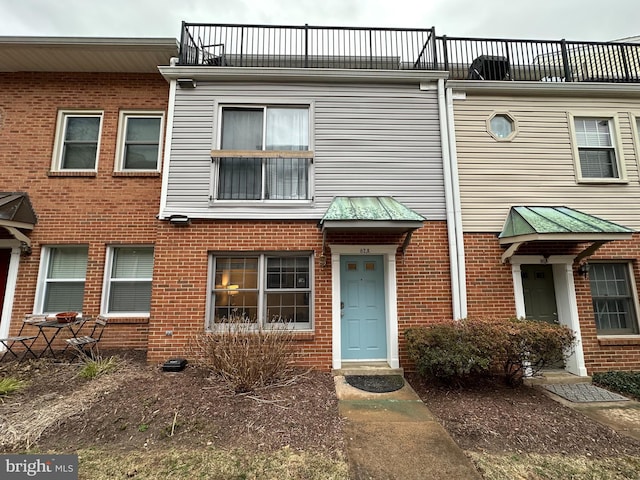 view of front of property featuring a balcony and brick siding