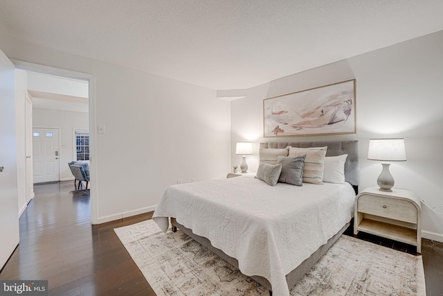 bedroom featuring wood-type flooring, a textured ceiling, and baseboards