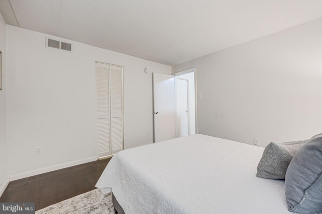 bedroom featuring a closet, visible vents, dark wood finished floors, and baseboards