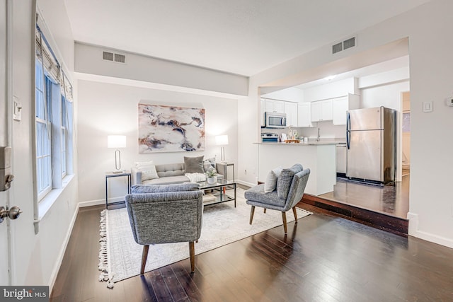 living room featuring baseboards, visible vents, and dark wood finished floors