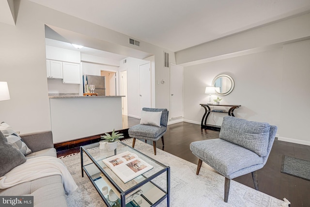 living area with visible vents, baseboards, and wood finished floors