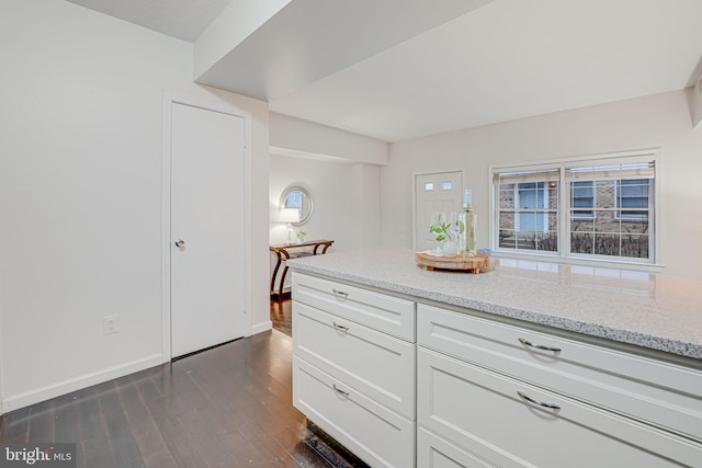 kitchen featuring baseboards, light stone counters, dark wood-style flooring, and white cabinets