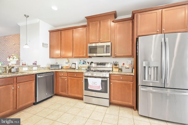 kitchen featuring sink, stainless steel appliances, light stone countertops, and pendant lighting