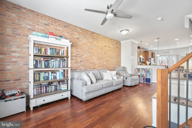 living room with brick wall, ceiling fan, and dark wood-type flooring