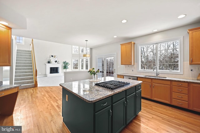 kitchen featuring sink, light stone counters, decorative light fixtures, appliances with stainless steel finishes, and a kitchen island