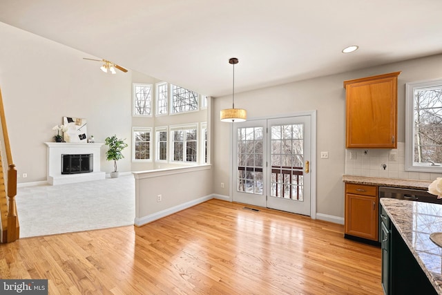 kitchen with pendant lighting, a fireplace, decorative backsplash, and light hardwood / wood-style flooring