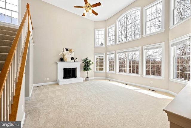 unfurnished living room with a towering ceiling, light colored carpet, and a fireplace