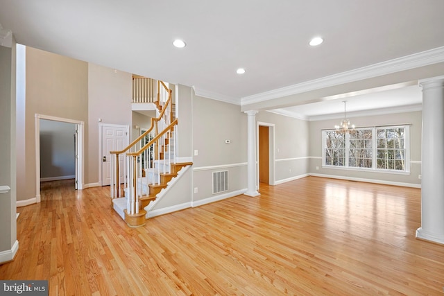 unfurnished living room with ornamental molding, decorative columns, light hardwood / wood-style floors, and a chandelier