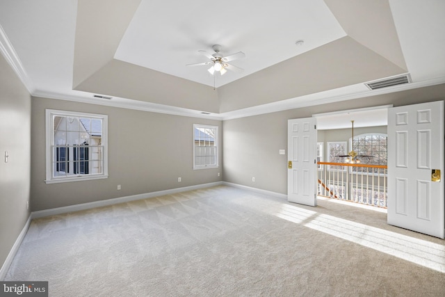 carpeted empty room featuring a raised ceiling, ornamental molding, a wealth of natural light, and ceiling fan