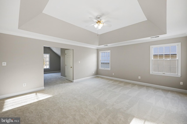 carpeted spare room with a raised ceiling and ceiling fan