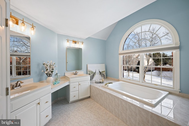 bathroom with a relaxing tiled tub, lofted ceiling, vanity, and tile patterned flooring