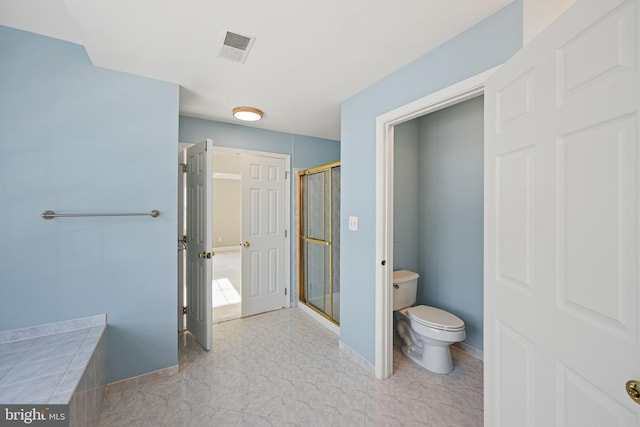 bathroom featuring a shower with door and toilet