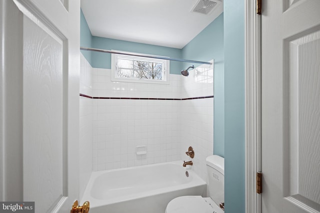 bathroom featuring tiled shower / bath combo and toilet