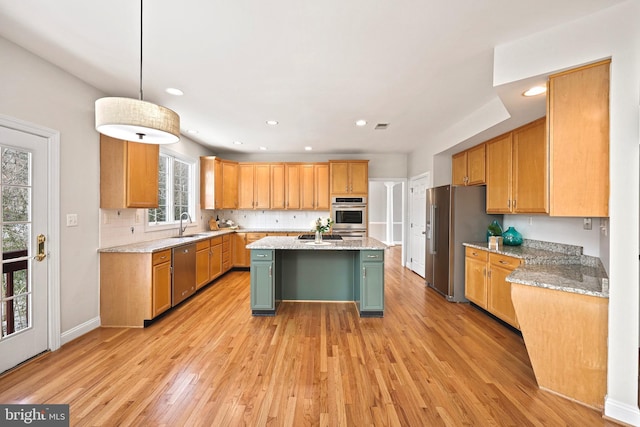 kitchen with a kitchen island with sink, light stone counters, light hardwood / wood-style floors, and appliances with stainless steel finishes