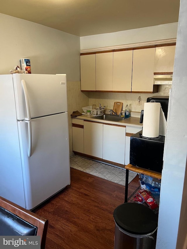 kitchen featuring white refrigerator, cream cabinetry, dark hardwood / wood-style flooring, and sink