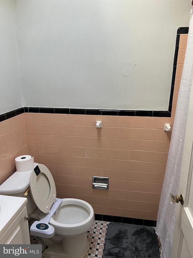 bathroom featuring toilet, tile patterned floors, tile walls, and vanity