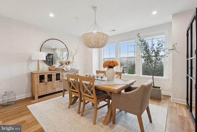 dining space with a notable chandelier and light wood-type flooring