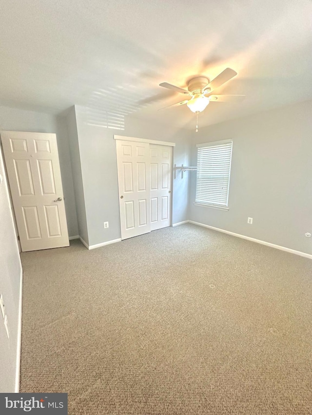 unfurnished bedroom featuring ceiling fan, a closet, and carpet flooring