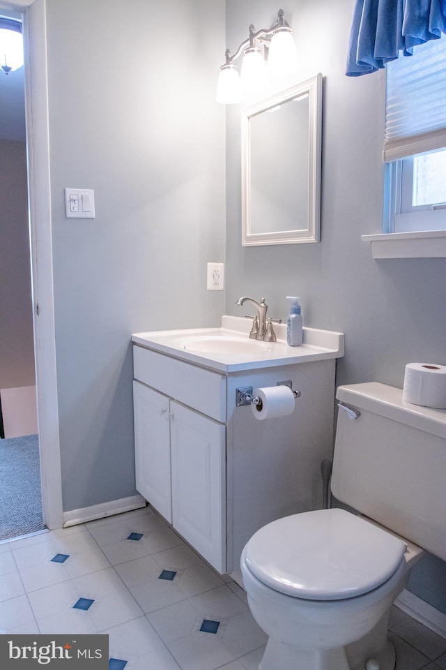 bathroom with toilet, vanity, and tile patterned floors