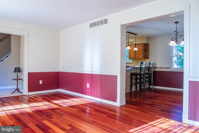 spare room with a chandelier and hardwood / wood-style flooring