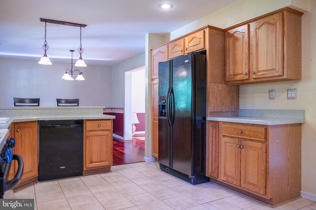 kitchen featuring black appliances, kitchen peninsula, an inviting chandelier, hanging light fixtures, and light tile patterned floors