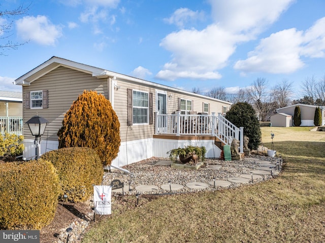 manufactured / mobile home with a front lawn and a wooden deck