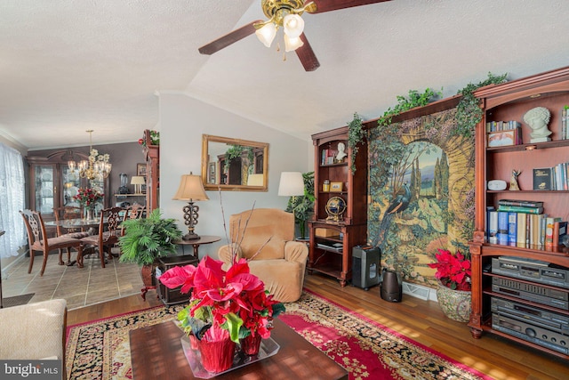 living room featuring vaulted ceiling, a textured ceiling, ceiling fan with notable chandelier, and hardwood / wood-style flooring