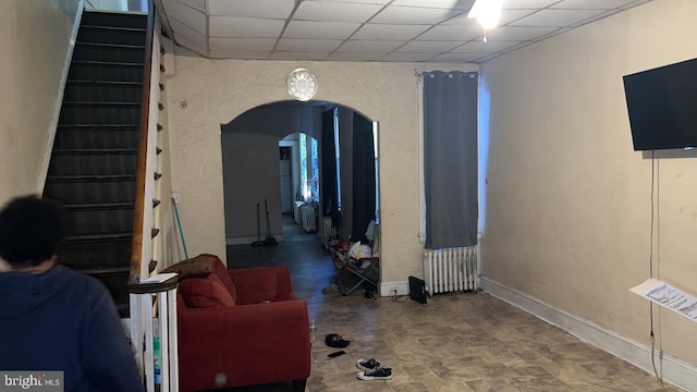 living room with a drop ceiling and radiator