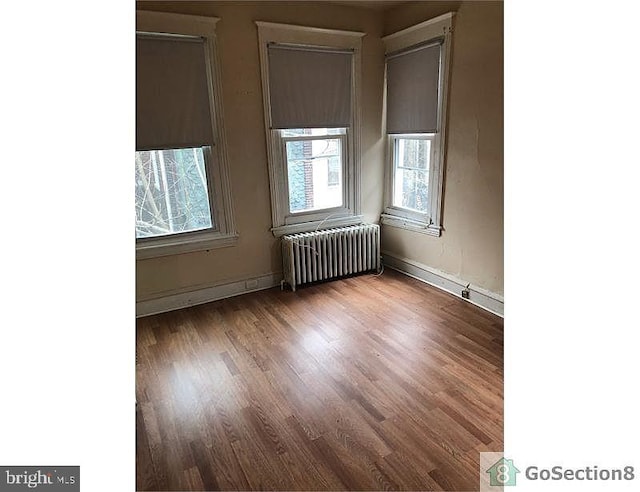 unfurnished room with hardwood / wood-style flooring and radiator heating unit