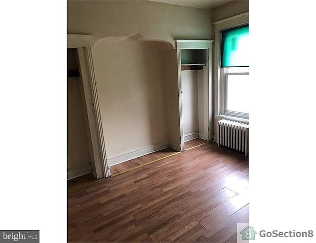 unfurnished bedroom featuring dark hardwood / wood-style floors and radiator