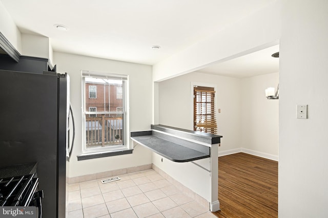 kitchen with gas stove, light tile patterned floors, and stainless steel refrigerator