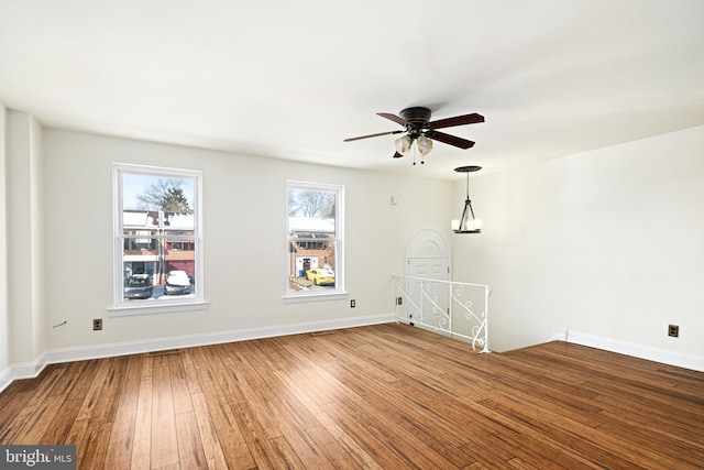 unfurnished living room with ceiling fan with notable chandelier and hardwood / wood-style floors