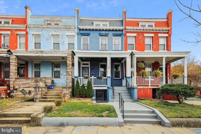 view of property featuring covered porch, mansard roof, and brick siding