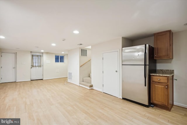 kitchen featuring light wood-style flooring, recessed lighting, freestanding refrigerator, and brown cabinets