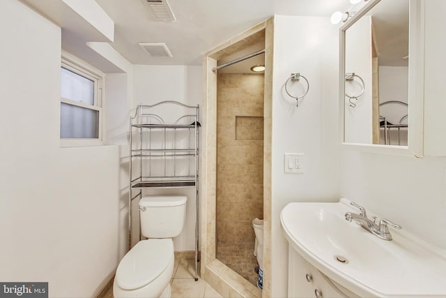 bathroom with visible vents, tiled shower, a sink, and toilet