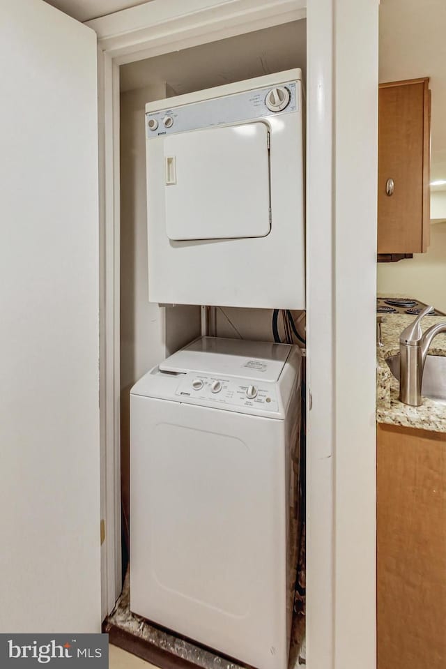 laundry room with laundry area, stacked washer / dryer, and a sink