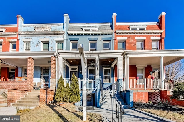 townhome / multi-family property featuring covered porch, mansard roof, and brick siding