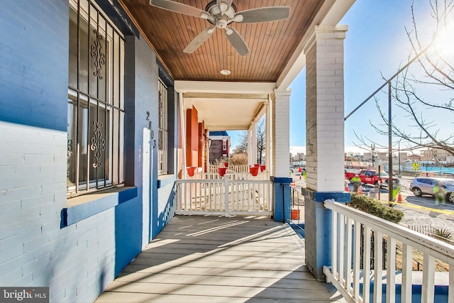 wooden deck featuring covered porch and ceiling fan