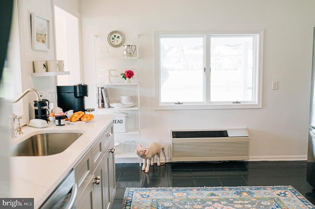 kitchen with an AC wall unit, dark tile patterned floors, a healthy amount of sunlight, and sink