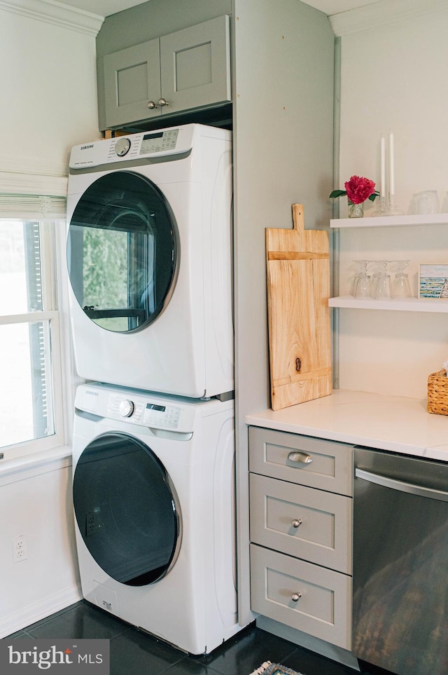 laundry area featuring a healthy amount of sunlight, ornamental molding, and stacked washer and clothes dryer