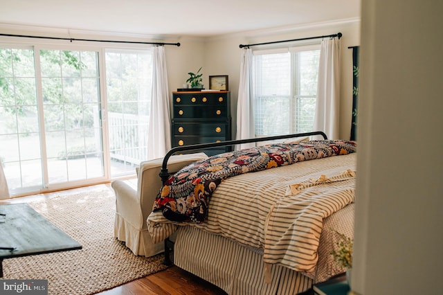 bedroom featuring wood-type flooring, access to exterior, and ornamental molding